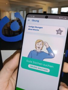 Porträt eines Mädchens mit Trisomie 21, das in einer Online-Unterrichtsstunde in die Kamera winkt.