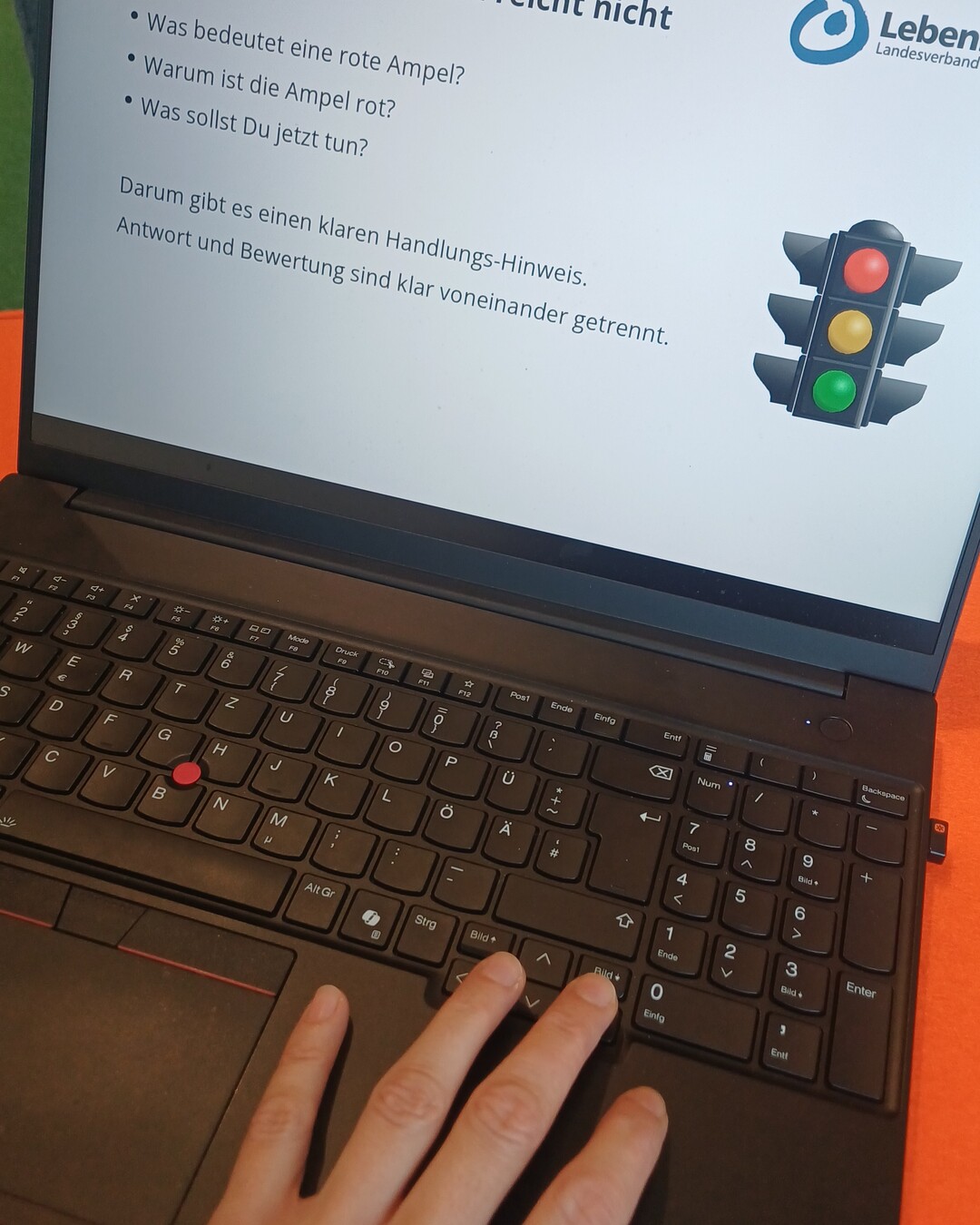 03-ampelsystem Laptop mit einer Präsentationsfolie und einer Ampel. Die Folie erklärt, dass eine Ampelfarbe allein nicht ausreicht und durch einen klaren Handlungshinweis ergänzt werden muss.